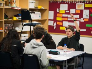 Student with hands up in Geography class